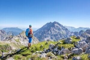 Randonneur équipé d’un sac à dos face à un panorama alpin, avec sommets rocheux et ciel dégagé dans les Hautes-Alpes.